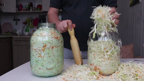 A man puts chopped cabbage and carrots with dill seeds in a jar. Compacts the Stock Footage 220713353