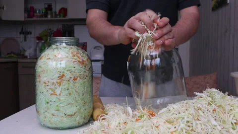 A man puts chopped cabbage and carrots with dill seeds in a jar. Compacts the Stock Footage 220713378