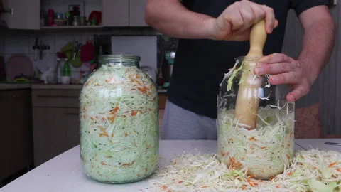 A man puts chopped cabbage and carrots with dill seeds in a jar. Compacts the Stock Footage 220713410