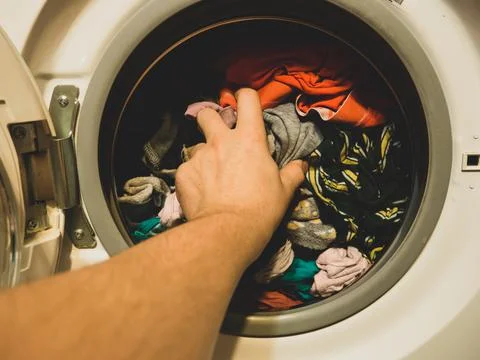 Man puts clothes in the washing machine, close-up Stock Photos