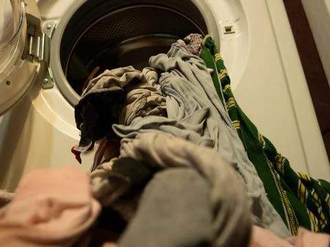 Man puts clothes in the washing machine, close-up Stock Photos
