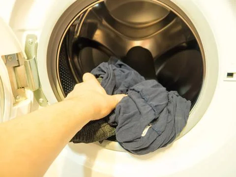 Man puts clothes in the washing machine, close-up Stock-Fotos