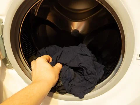 Man puts clothes in the washing machine, close-up Stock Photos