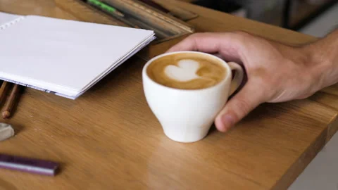 Man puts coffee with heart on table with art accessories Video stock 138637269