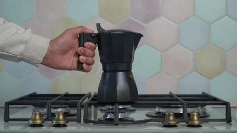 A man puts a coffee pot on the kitchen stove Stock Footage 196581850
