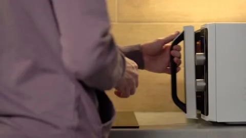 Man puts cup in microwave standing on table in home kitchen 库存影片 231174338