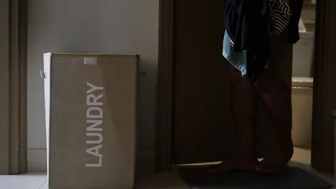A Man puts dirty clothes in the laundry basket in the hotel room 스톡 동영상 331375750