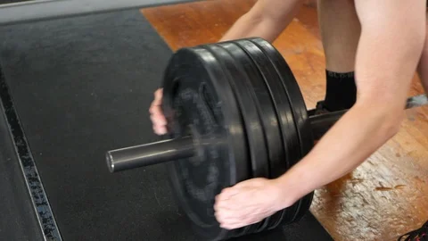 Man puts a disc weight on a barbell. CLOSE UP. Video stock 108411911
