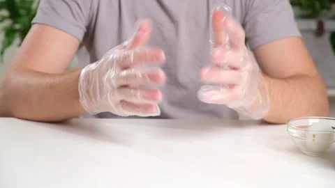 A man puts disposable plastic gloves on his hands to dye Easter eggs. Coloring Stock Footage 236659996
