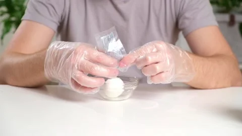 A man puts disposable plastic gloves on his hands to dye Easter eggs. Coloring Stock Footage 236660013