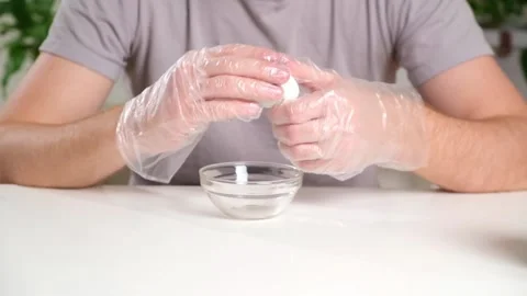 A man puts disposable plastic gloves on his hands to dye Easter eggs. Coloring Stock Footage 236660019