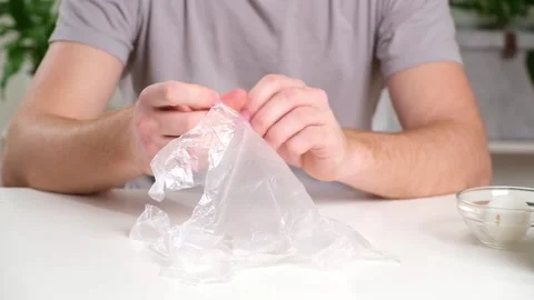 A man puts disposable plastic gloves on his hands to dye Easter eggs. Coloring Stock Footage 236660047