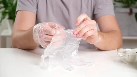 A man puts disposable plastic gloves on his hands to dye Easter eggs. Coloring Stock Footage 236660060