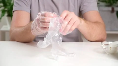 A man puts disposable plastic gloves on his hands to dye Easter eggs. Coloring Stock Footage 236921544