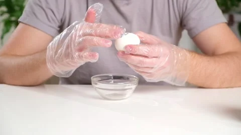 A man puts disposable plastic gloves on his hands to dye Easter eggs. Coloring Stock Footage 237858489