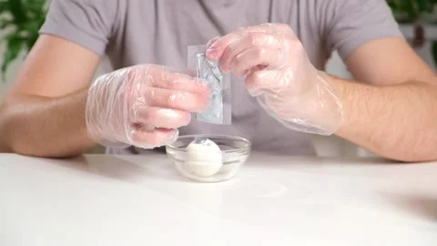 A man puts disposable plastic gloves on his hands to dye Easter eggs. Coloring Stock Footage 238501319