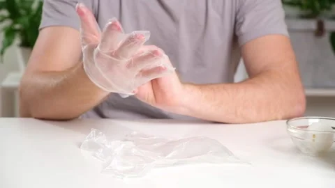 A man puts disposable plastic gloves on his hands to dye Easter eggs. Coloring Stock Footage 241424136