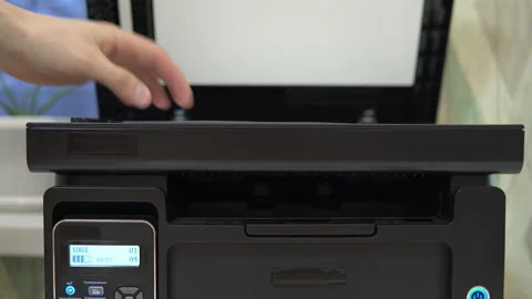 A man puts a document on the scanner to scan and tries to start Stock Footage 146318747
