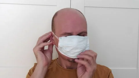 A man puts on a double protective hygienic disposable medical mask to protect Stock Footage 152343077