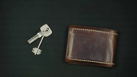 Man puts down brown leather wallet and keys on black surface. Top view Stock Footage 297398135