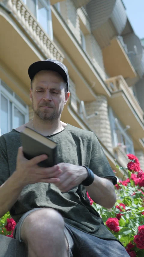 Man puts down phone and picks up book. vertical video Stock Footage 313359843