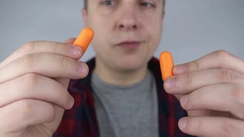 The man puts on earplugs. Close-up of an orange noise barrier. Deep sleep. The E Stock Footage 187969157