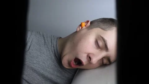 The man puts on earplugs. Close-up of an orange noise barrier. Deep sleep. The E Stock Footage 187969259