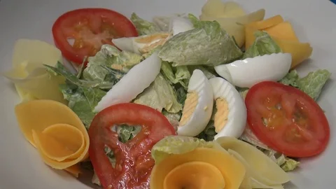 A man puts egg pieces on a salad on a plate - closeup Stock-Footage 82683111