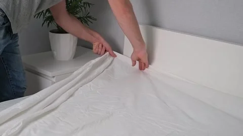 A man puts an elasticated sheet on mattress. Change of bed linen. Stock-Footage 188979100