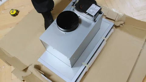 Man puts energy-saving exhaust hood onto cardboard sheet at home Stock Footage 304401337