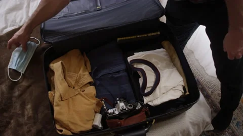 Man puts a face mask into his neatly packed suitcase and zips it up Stock-Footage 134285916
