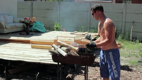 The man puts the firewood in the brazier. Stock-Footage 90288499