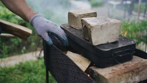 A man puts firewood in the grill on which food is being prepared Stock Footage 156464742