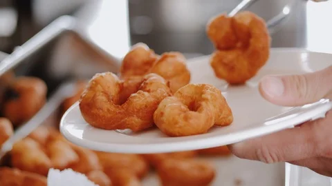 Man puts fresh crispy and sweet donut in plate, fried fat street food Stock Footage 111461558