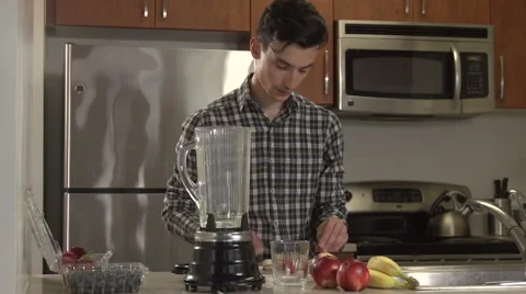 A man puts fruit into a blender in a kitchen. Stock Footage 44116987