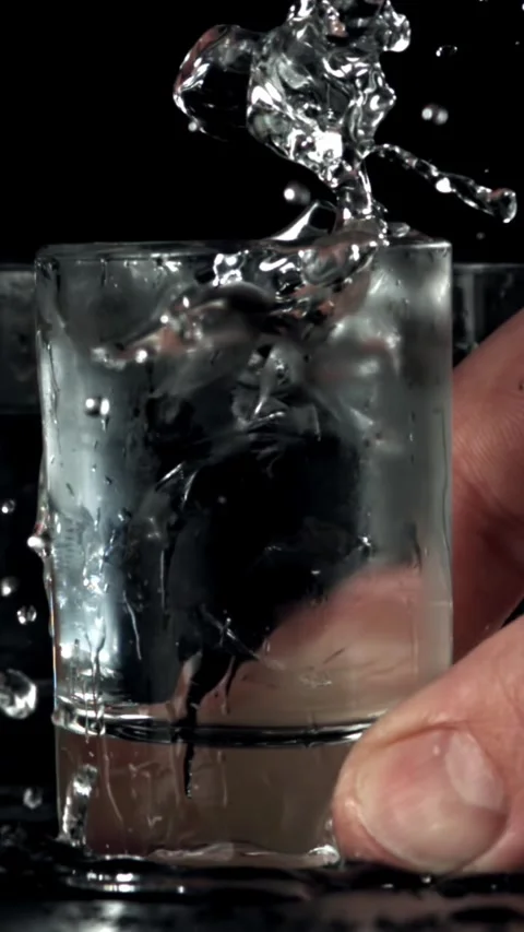 The man puts a glass of vodka on the table. Filmed on a high-speed camera at Stock Footage 335376049