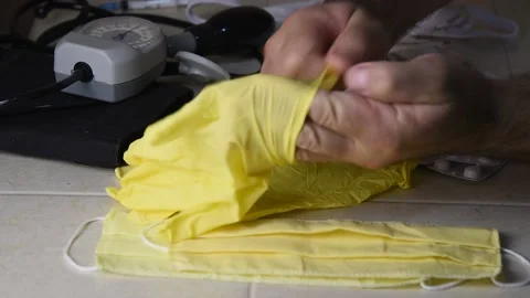 The man puts on gloves, then picks up an antiviral mask. Stock Footage 143595370