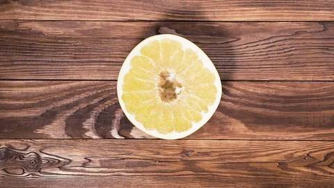 Man puts half an citrus X paradisi on wooden table. Video stock 85188073
