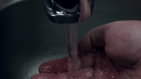 Man puts hand under running tap in stainless steel sink Stock Footage 104783280
