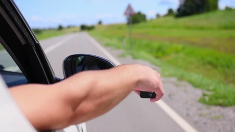 Man puts his hand out car window and vaping an electronic cigarette on a sunny Stock Footage 114980024
