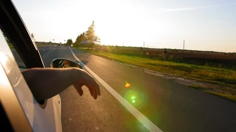 Man puts his hand out car window, feels the fresh air, on the sunset. Close up Stock Footage 115030231
