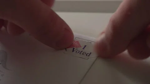 Man puts I Voted sticker on absentee mail in ballot sticker as postage Stock Footage 141214280