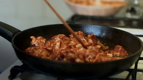  A man puts it in a pan and fries meat in tomato sauce in the home kitchen. Stock-Footage 127626475