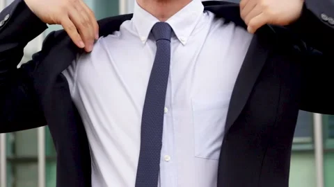 Man puts on jacket against the background of an office building. Stock Footage 153121723