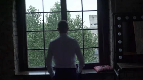 Man Puts On A Jacket At The Window Stock Footage 74700930