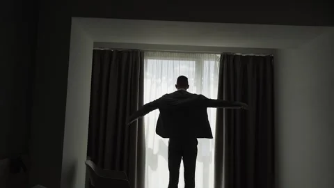 A man puts on a jacket by the window Stock Footage 328183263