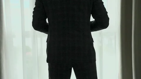 A man puts on a jacket by the window Stock Footage 328186497