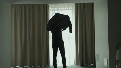 A man puts on a jacket by the window Video stock 328189781