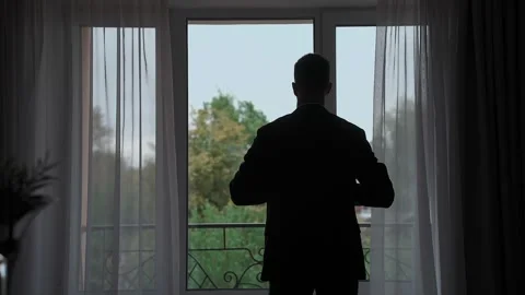 A man puts on a jacket by the window Video stock 328314902