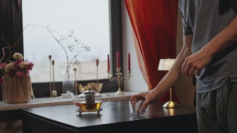 Man puts a kettle of tea and a cup on the table Stock Footage 294254129
